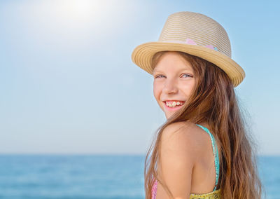 Portrait of a pretty smiling teenage girl on the background of the sea. 