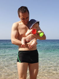 Father and son on the pebble beach with adriatic sea in background