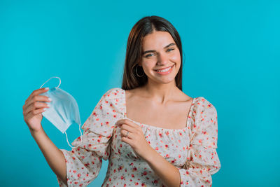 Portrait of smiling young woman against blue background