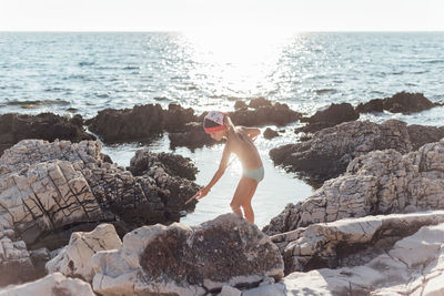 Full length of man on rock at beach against sky