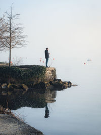 Man standing on rock against sky