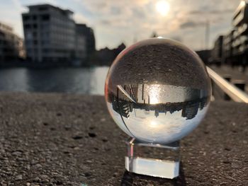 Close-up of crystal ball on river against buildings in city