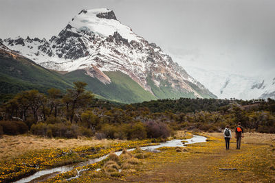 People on snowcapped mountain against sky