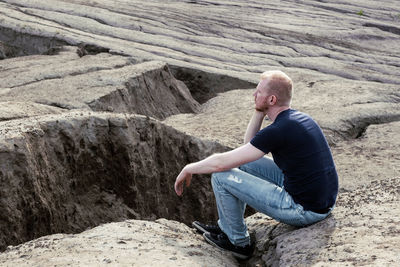 Side view of man sitting on rock