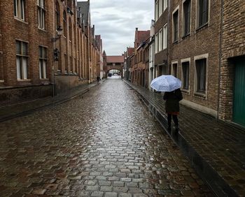 Rear view of person walking on wet street during rainy season