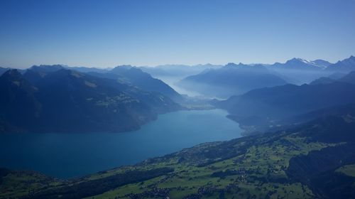 Scenic view of lake and mountains against clear blue sky