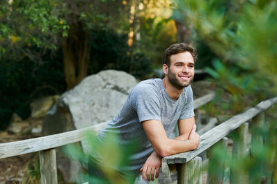 Portrait of young man standing against trees