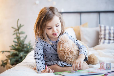 Girl looking away while relaxing on bed at home