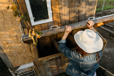 Morning routine on the farm, woman looks into the chicken coop to collect eggs