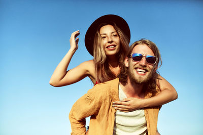 Portrait of smiling young couple against sky