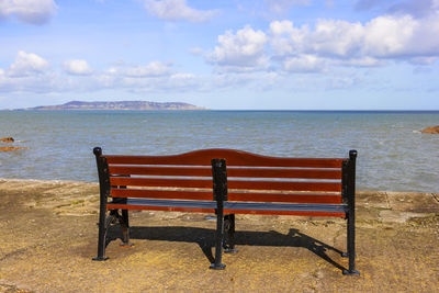 Empty chairs on beach against sky