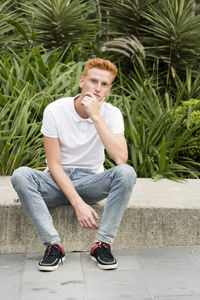 Full length of young man sitting on retaining wall