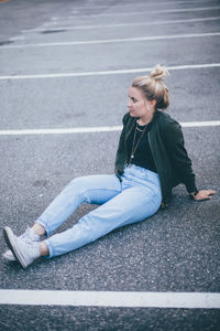 Full length of woman sitting on road