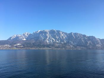 Scenic view of sea and mountains against clear blue sky