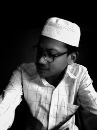 Man wearing skull cap against black background