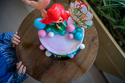 Underwater mermaid cake on the wooden table with child nearby. top view.