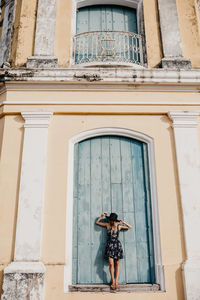 Woman standing against closed door in sunny day