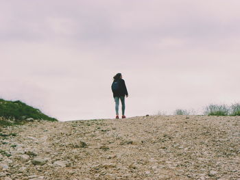 Rear view of woman standing on landscape against sky