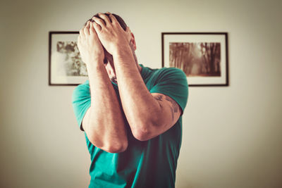 Side view of man with arms crossed against wall