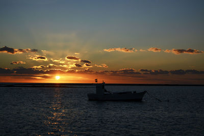 Silhouette boat in sea against sky during sunset