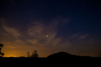 Silhouette landscape against sky at night