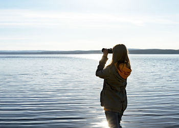 Rear view of man photographing sea against sky