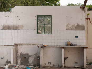Wall with window of an old room used as a kitchen of a ruined and abandoned house.