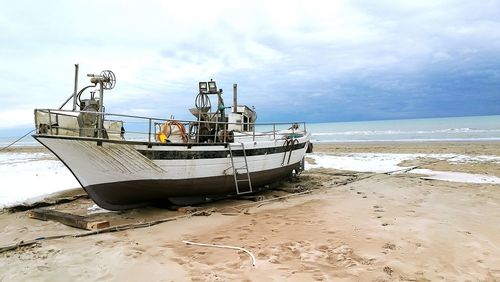 Boat moored on beach against sky