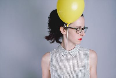 Close-up of young woman with balloons against gray background