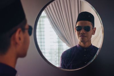 Young man reflecting in mirror at home