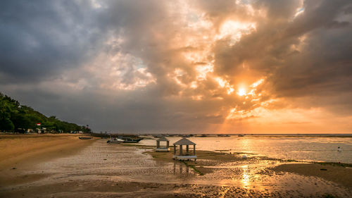 Scenic view of beach against cloudy sky during sunset