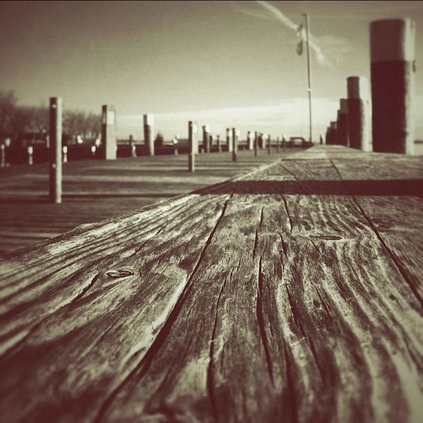 surface level, focus on foreground, selective focus, wood - material, in a row, close-up, wooden, diminishing perspective, the way forward, pattern, empty, no people, outdoors, day, wood, textured, metal, absence, sky, transportation