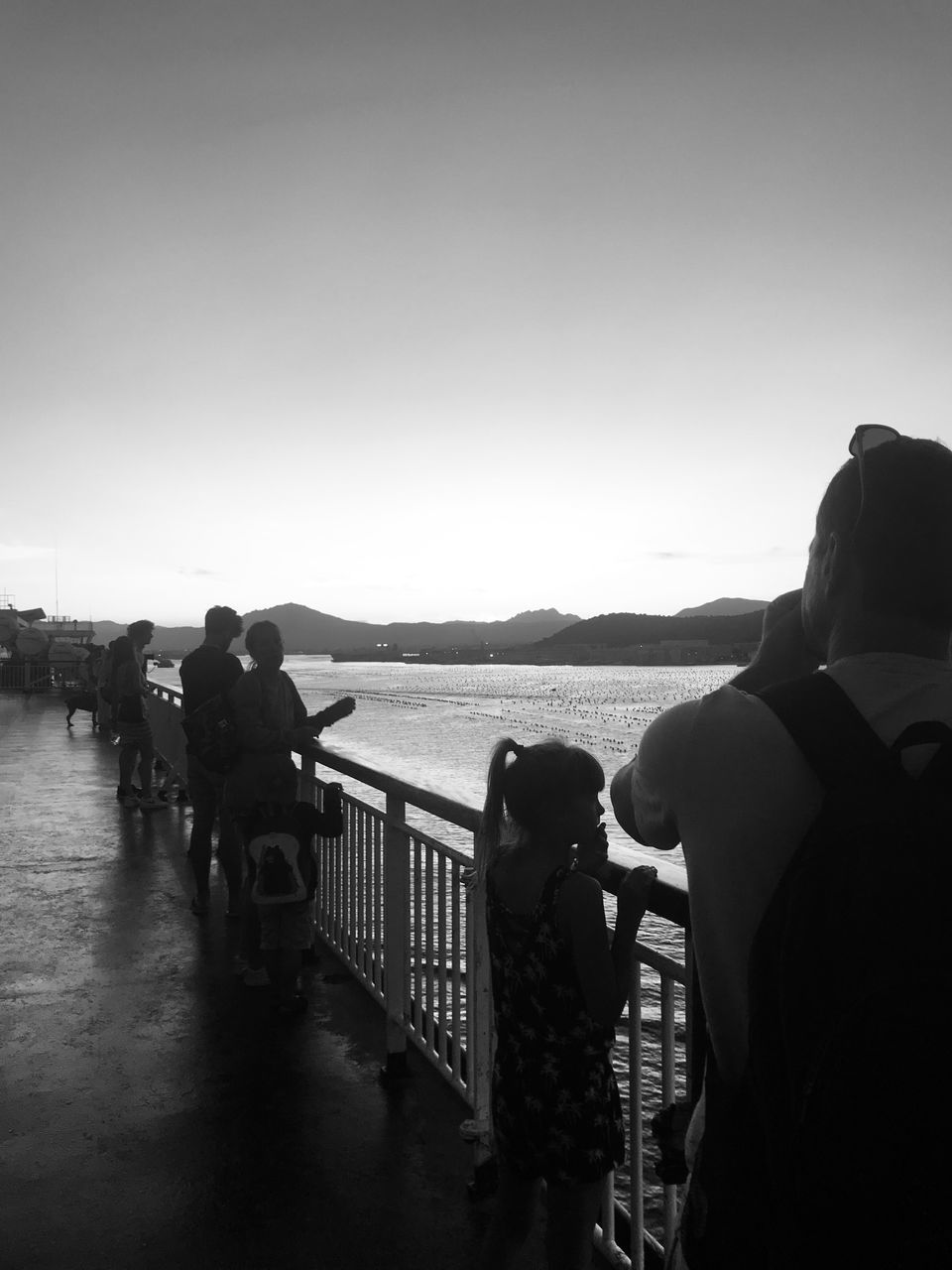 REAR VIEW OF PEOPLE LOOKING AT SEA AGAINST SKY