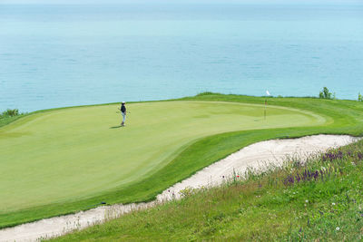 Scenic view of golf course by sea