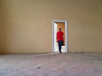 Rear view of man standing against door of building