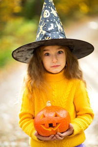 Portrait of girl holding pumpkin wearing halloween costume