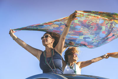 Woman traveling with friend in car against sky