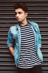 Young man standing against corrugated iron