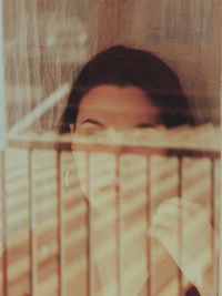 Young woman looking away seen through window