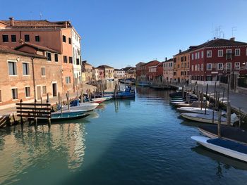 Boats moored in canal against buildings in city