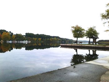 Reflection of trees in calm lake against clear sky