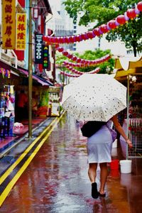 Rear view of woman walking on wet umbrella