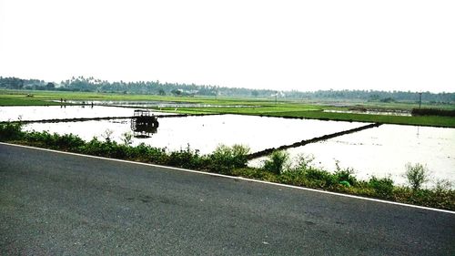 Road by lake against clear sky