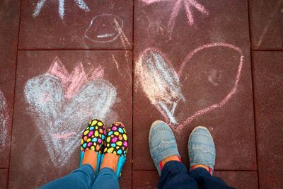 Low section of girls standing on drawings over street