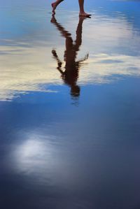 Low section of person walking on beach against sky