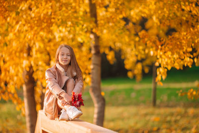 Portrait of cute girl sitting on railing in park