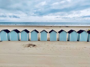 Scenic view of beach huts in a row on beach against sky