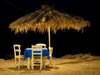 Chairs on table at beach at night