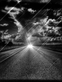 Sun shining through clouds over road