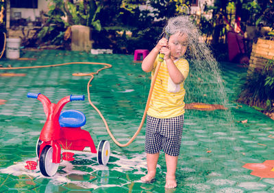 High angle view of boy washing tricycle outdoors